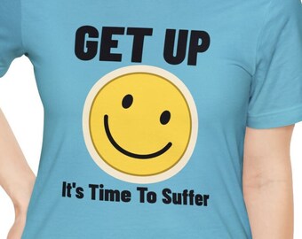 May include: A light blue t-shirt with the text "GET UP" in black, a yellow smiley face, and the text "It's Time To Suffer" in black.