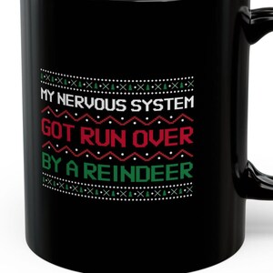 Peut inclure: Mug à café noir avec un motif blanc, vert et rouge. Le texte sur le mug est "My nervous system got run over by a reindeer."