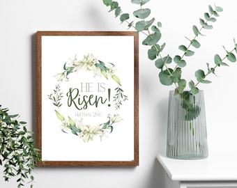 May include: A framed print with a white floral wreath and the text "He is Risen!" with the scripture reference "Matt. 28:6".