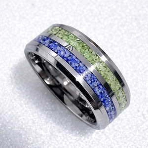 May include: A silver-toned ring with a polished finish. The ring features two bands of inlaid crushed stone in blue and green, separated by a silver band. The ring's design is modern and geometric, suitable for everyday wear.