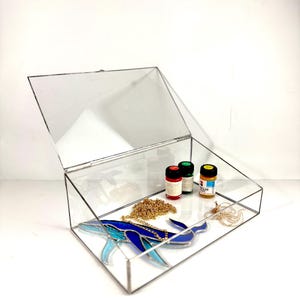 May include: A clear glass display box with a hinged lid, containing a blue stained glass whale, gold chain, and three small bottles of paint. The bottles are red, green, and yellow.