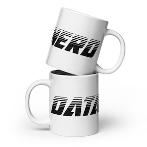 Peut inclure: Deux tasses en céramique blanche empilées l'une sur l'autre. La tasse du haut porte le mot "NERD" imprimé en noir avec une police de caractères rétro. La tasse du bas porte le mot "DATA" imprimé en noir avec une police de caractères rétro.