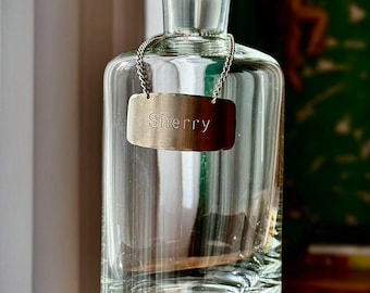 Vintage helderglazen sherrykaraf met zilverkleurig label, zware fles bar, decor drankenkast