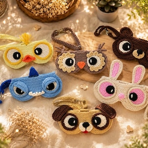 Puede incluir: Una colección de estuches para gafas hechos a mano con ganchillo, con diseños de animales como un pollito amarillo, un tiburón azul, un búho marrón, un oso pardo, un conejo beige y un perro canela. Cada estuche tiene detalles faciales.