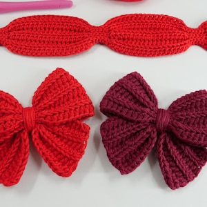 Puede incluir: Lazos de ganchillo hechos a mano en rojo y burdeos, con una textura acanalada. La imagen muestra lazos en diferentes etapas de finalizaci&oacute;n, junto con un ganchillo rosa e hilo rojo. Artesan&iacute;a.