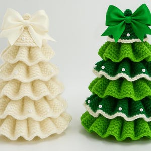 K&ouml;nnte beinhalten: Zwei handgefertigte Weihnachtsbaumdekorationen. Eine ist elfenbeinfarben mit einer cremefarbenen Schleife, die andere ist gr&uuml;n mit einer gr&uuml;nen Schleife. Beide sind gestrickt mit einem R&uuml;schendesign und mit kleinen wei&szlig;en Perlen verziert.