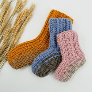 May include: Three pairs of knitted socks in different colors: mustard yellow, blue, and pink. Each sock has a contrasting color stripe at the ankle.