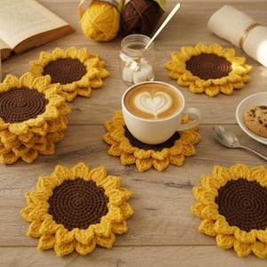 May include: Handmade crochet sunflower coasters in yellow and brown. The coasters are arranged on a wooden surface with a cup of coffee, cookies, and a book. The coasters are approximately 5 inches in diameter.
