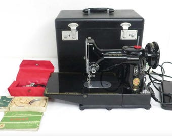 May include: Black Singer sewing machine with a black carrying case, red accessories pouch, and several small boxes. The machine has a foot pedal and power cord. The machine is a vintage model.