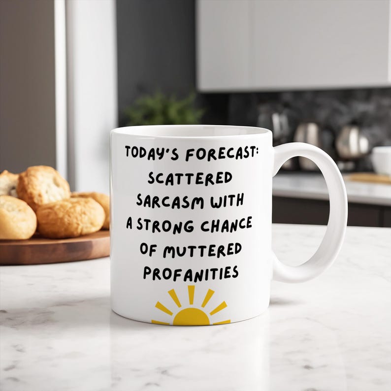 May include: White ceramic mug with a black and yellow sun graphic. The mug reads "Today's Forecast: Scattered Sarcasm with a Strong Chance of Muttered Profanities."
