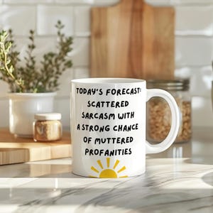 May include: White ceramic mug with a black and yellow design. The mug reads "Today's Forecast: Scattered Sarcasm with a Strong Chance of Muttered Profanities".