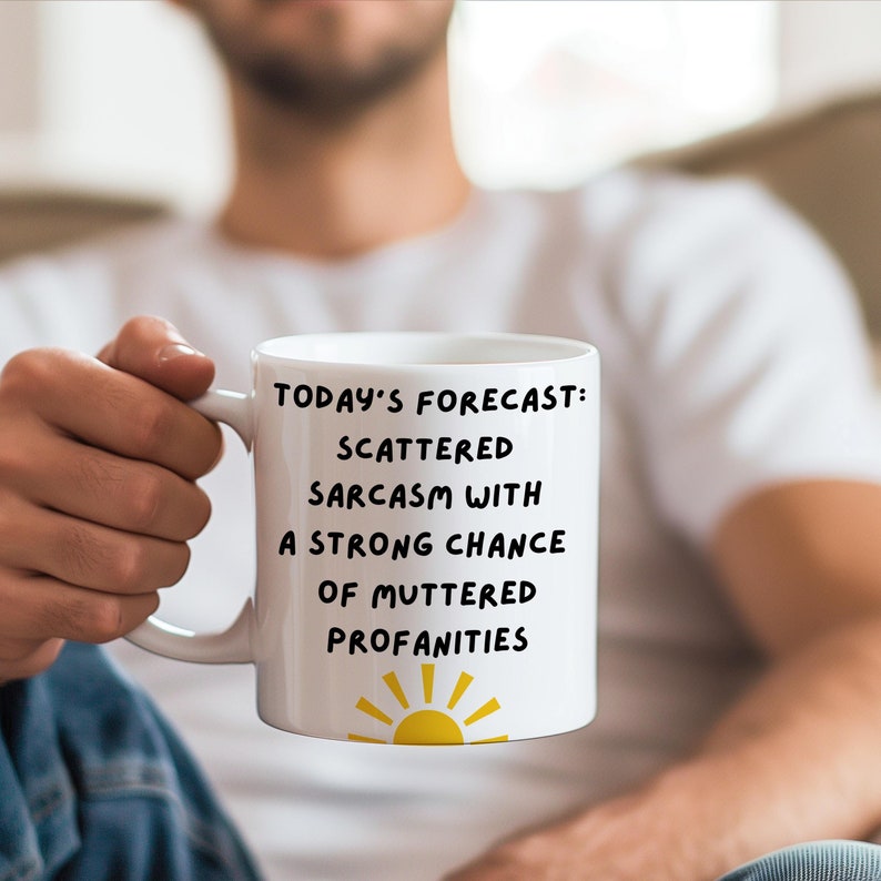 May include: White ceramic mug with a black graphic that reads "Today's forecast: Scattered sarcasm with a strong chance of muttered profanities". A yellow sun graphic is at the bottom of the mug.
