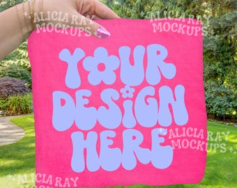 Komfortfarben Neon Pink 1717 Erwachsenen T-Shirt Mockup | Outdoor Mockup | DTF MockUp | Trendiges Mockup | Hand, die gefaltetes Hemd hält | Außen Mock