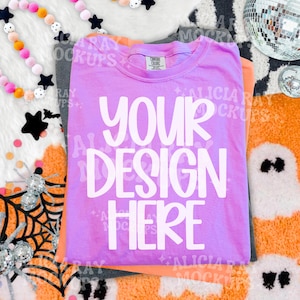 May include: A bright purple short-sleeved t-shirt with a crew neckline and the white text YOUR DESIGN HERE printed in a bold, rounded font on the front. The garment features a Comfort Colors brand label inside the collar area.
