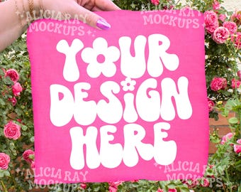Komfortfarben Neon Pink 1717 Erwachsenen T-Shirt Mockup | Outdoor Mockup | DTF MockUp | Trendiges Mockup | Hand die gefaltetes Hemd hält