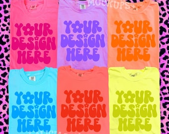 May include: Six colorful t-shirts, each with the text "YOUR DESIGN HERE" in a retro font. The shirts are in shades of pink, purple, orange, blue, coral, and yellow. The background is a pink leopard print.