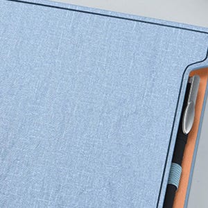 May include: A light blue notebook with a pen holder and a black pen inserted. The notebook has a textured fabric cover.