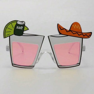 May include: White plastic party glasses with pink lenses. The glasses are shaped like shot glasses with a lime wedge and salt shaker on one side and a sombrero on the other side.