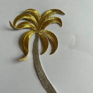 May include: Gold palm tree embroidery patch with a silver trunk. The palm tree has a detailed design with multiple fronds.