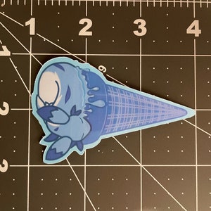 May include: A blue ice cream cone with a cartoon character melting out of it. The ice cream is dripping down the side of the cone.