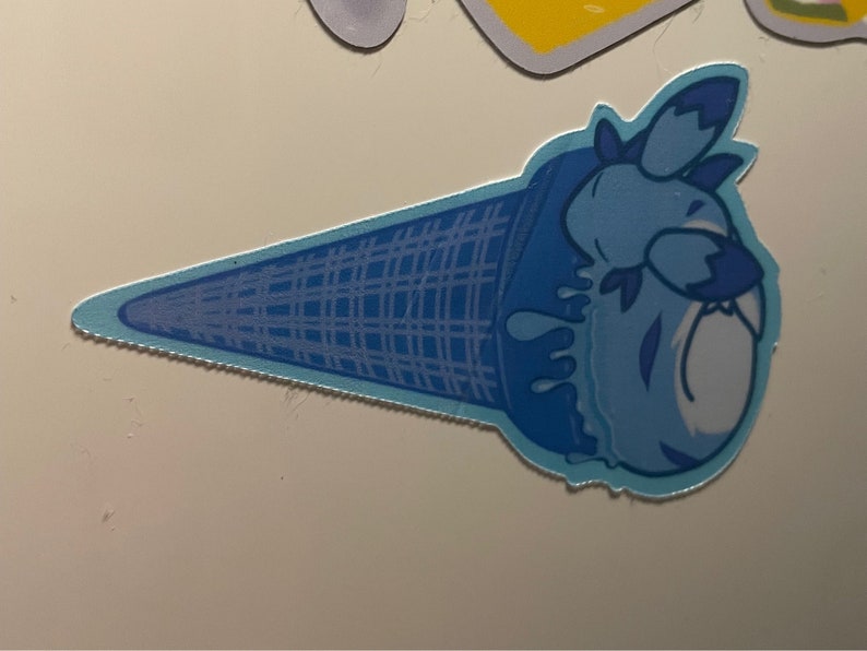 May include: A blue ice cream cone with a blue and white cartoon character on top. The ice cream is melting and dripping down the cone.
