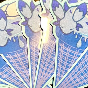 May include: A set of blue and white ice cream cone stickers with a cartoon character design. The character is a blue creature with a white face and purple eyes. The ice cream is dripping down the cone.