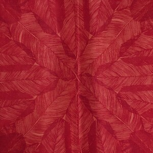 May include: A red fabric with a repeating pattern of stylized, light brown feathers.
