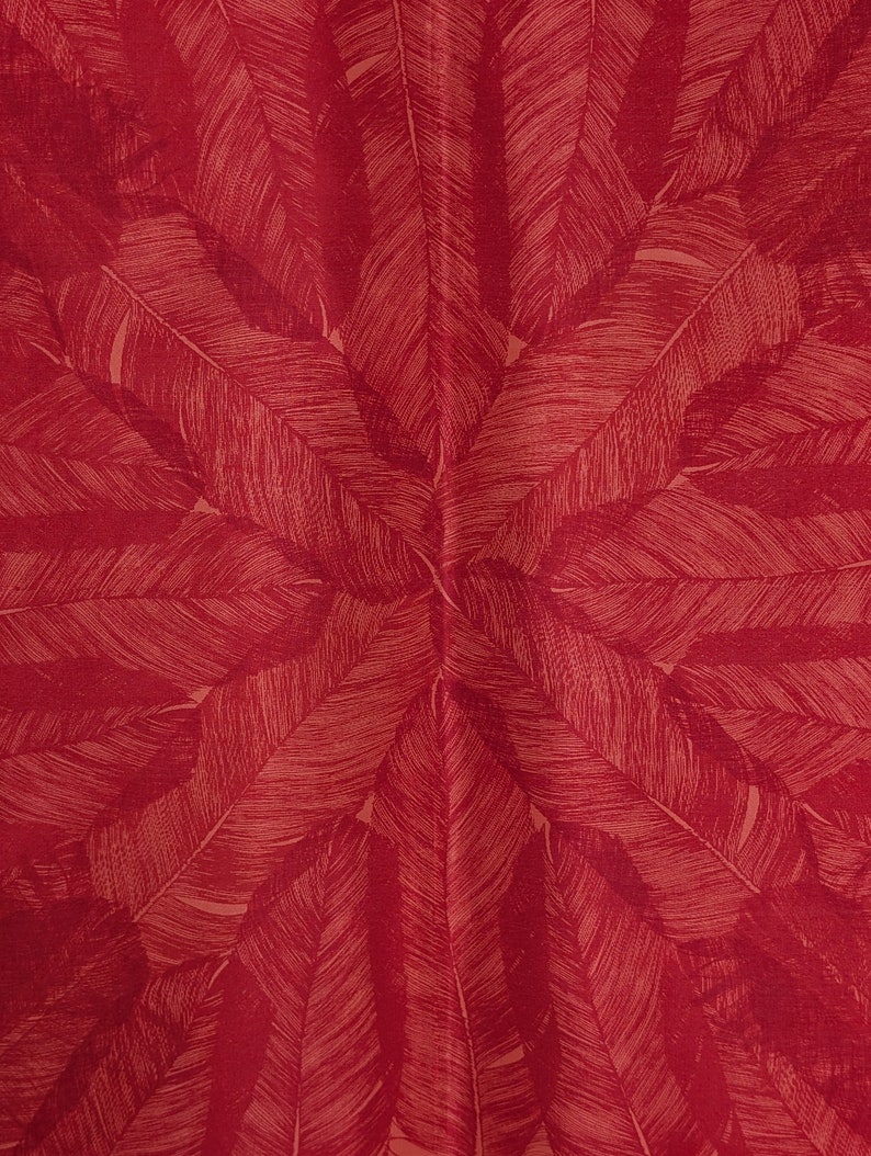 May include: A red fabric with a repeating pattern of stylized, light brown feathers.