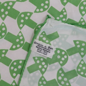 May include: Green and white mushroom patterned silk scarf with a white tag that reads "Scarves by Visna 100% Polyester Machine Washable Drip Dry made in Japan"