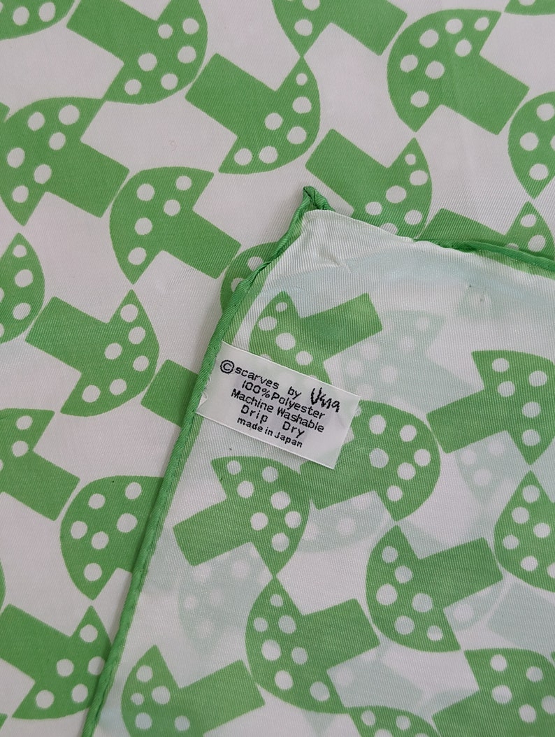 May include: Green and white mushroom patterned silk scarf with a white tag that reads "Scarves by Visna 100% Polyester Machine Washable Drip Dry made in Japan"