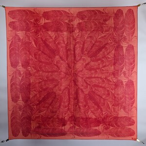 May include: A red silk scarf with a pattern of white feathers arranged in a circular design.