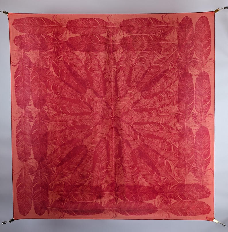 May include: A red silk scarf with a pattern of white feathers arranged in a circular design.