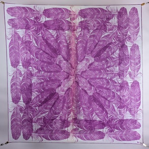 May include: A white square scarf with a purple feather pattern. The feathers are arranged in a symmetrical pattern, radiating from the center of the scarf.