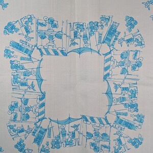 May include: A white tablecloth with a blue and white pattern of people and stalls at a market. The design is repeated around the border of the tablecloth.