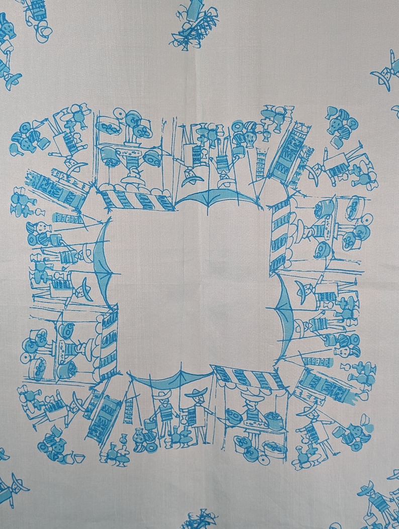 May include: A white tablecloth with a blue and white pattern of people and stalls at a market. The design is repeated around the border of the tablecloth.