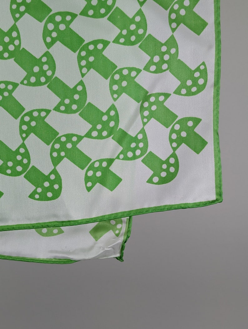 May include: A white silk scarf with a green mushroom pattern. The mushrooms have white polka dots.