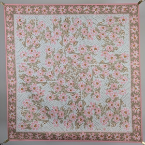 May include: A square pink and brown floral patterned fabric with a white background. The fabric has a repeating pattern of pink flowers with brown centers and brown leaves. The fabric is surrounded by a pink border with a white polka dot pattern.