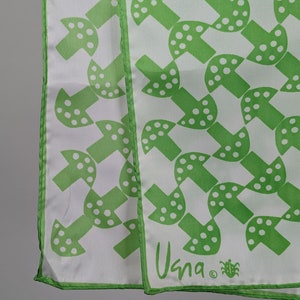 May include: Green and white patterned silk scarf with a white background and green mushroom design. The scarf has a green border and the text "Usna" in green.
