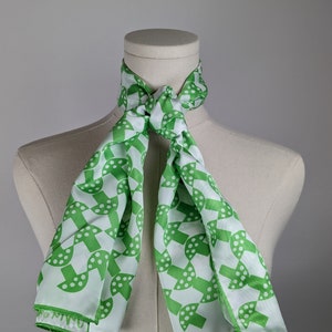 May include: A white silk scarf with a green geometric pattern of circles and dots. The scarf is tied around a white mannequin's neck.