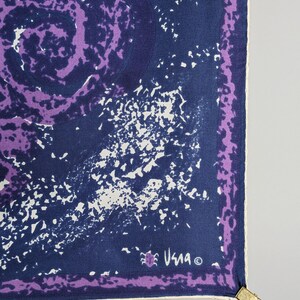 May include: A purple and blue silk scarf with a white and blue abstract design. The scarf has a white border and the signature "Usma" in the bottom right corner.