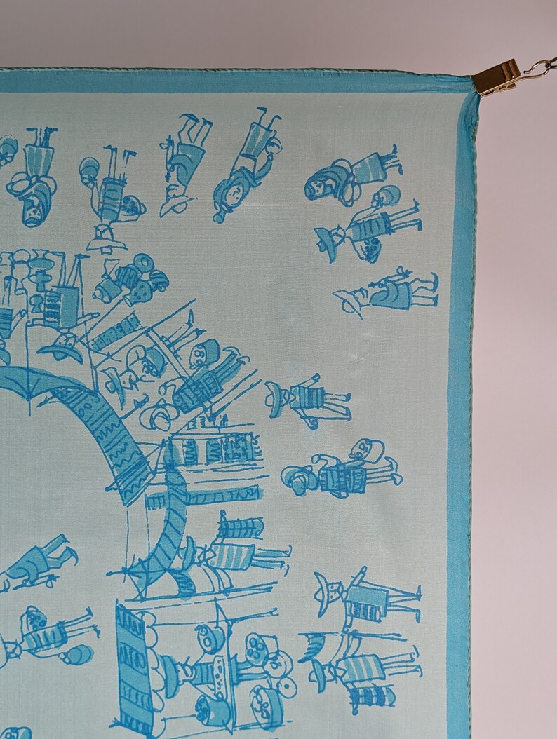May include: A light blue silk scarf with a white border and a pattern of blue stick figures. The figures are wearing hats and carrying objects.