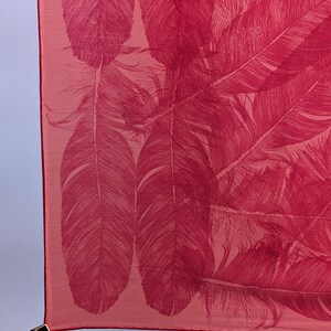 May include: A pink fabric scarf with a red feather pattern.