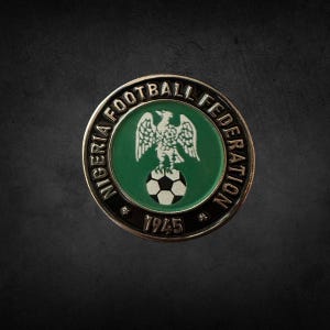以下が含まれることがあります： ナイジェリアサッカー連盟のロゴが入った円形の金属製ピンバッジ。緑と白を基調としたデザインで、縁には「NIGERIA FOOTBALL FEDERATION」の文字。中央にはサッカーボールの上に鷲が描かれ、下部には年号「1945」が記されています。