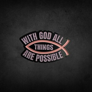 Puede incluir: Pin de esmalte negro y rosa con un símbolo de pez y el texto "Con Dios todo es posible."