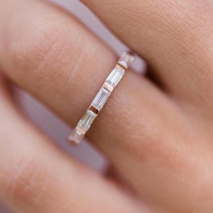 May include: A delicate gold band ring with a row of baguette-cut diamonds.