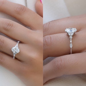 May include: A close-up of two hands wearing engagement rings with oval-shaped center stones and pave diamond accents. The rings are set in white gold.