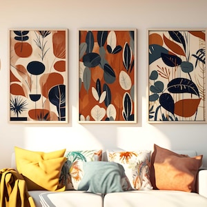Puede incluir: Tres impresiones de arte abstracto enmarcadas con un diseño moderno y minimalista. Las impresiones presentan un patrón de hojas estilizadas y formas orgánicas en tonos de azul, naranja y blanco.