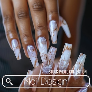 Puede incluir: Primer plano de una mano con uñas largas y blancas con un diseño de mármol y detalles dorados. Las uñas son largas y puntiagudas. La imagen está etiquetada como "Nail Design" y "Stock Photo Collection".