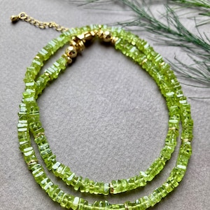 Può includere: Una collana a doppio filo realizzata con perline di peridoto verde chiaro e dettagli dorati.