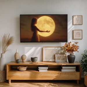 May include: A living room setup featuring a large television displaying a woman reaching for a glowing moon. Below, a wooden cabinet holds decorative vases, a woven basket, books, and framed artwork. Dried floral arrangements add warmth.
